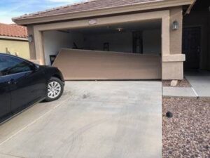 Residential garage door knocked off its tracks and collapsed outward into the driveway after being hit by a vehicle.