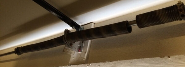 Close-up of damaged garage door torsion spring above door.