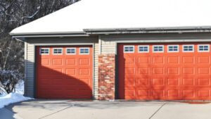 Modern home with double red garage doors in winter.