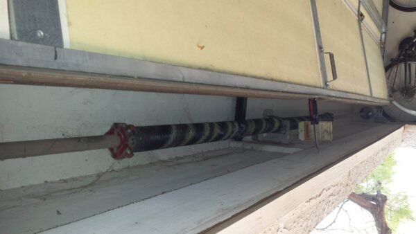 Close-up view of a garage door torsion spring mounted above the door