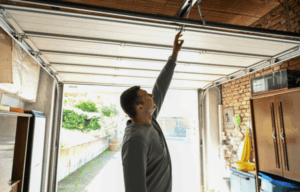 Homeowner inspecting garage door track and opener system for safety and maintenance issues